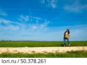 Young woman hitch hiking on a beautiful green meadow. Стоковое фото, агентство Ingram Publishing / Фотобанк Лори