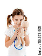 Beautiful little girl pretending to be a nurse and auscultate her teddy-bear. Стоковое фото, агентство Ingram Publishing / Фотобанк Лори