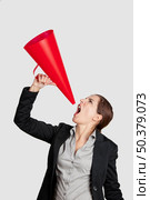 Business young woman speaking to a megaphone, isolated on white. Стоковое фото, агентство Ingram Publishing / Фотобанк Лори