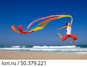 Beautiful young woman jumping on  the beach with a colored tissue. Стоковое фото, агентство Ingram Publishing / Фотобанк Лори