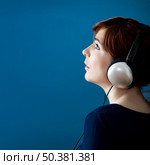 Young woman listen music with headphones over a blue wall. Стоковое фото, агентство Ingram Publishing / Фотобанк Лори