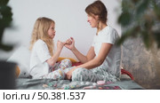 Smiling mother and daughter enjoy funny makeup moment together, showing unconditional love, emotional closeness in safe, familiar home space. Cross your fingers and play game make up and fight no more. Стоковое видео, видеограф Енваев Андрей / Фотобанк Лори