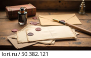 Antique still life with old letters with wax seals, fountain pen, and inkwell on vintage wooden desk by window. Стоковое AI-изображение, AI-художник Павел Муравьев / Фотобанк Лори