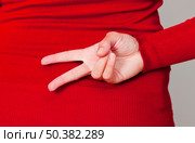 Woman hiding her hand and doing a gesture behind the backs. Стоковое фото, агентство Ingram Publishing / Фотобанк Лори