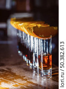 A number of shots with golden tequila and orange slices. Close-up. Стоковое фото, агентство Ingram Publishing / Фотобанк Лори
