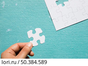 hand holding cardboard white jigsaw puzzle blue textured backdrop. Стоковое фото, агентство Ingram Publishing / Фотобанк Лори