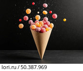 Kraft paper bag with scattered dragee candies on black background. Стоковое AI-изображение, AI-художник Анна Никонорова / Фотобанк Лори