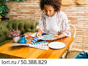 woman matching color swatch with plate table. Стоковое фото, агентство Ingram Publishing / Фотобанк Лори