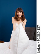 Beautiful young woman throwing a pillow, and start a pillow fight. Стоковое фото, агентство Ingram Publishing / Фотобанк Лори