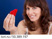 Beautiful young woman holding and showing a big and fresh strawberry. Стоковое фото, агентство Ingram Publishing / Фотобанк Лори