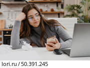 bored woman checking her phone while working from home. Стоковое фото, агентство Ingram Publishing / Фотобанк Лори