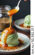 A close-up of a spoon swirling a fusion dessert miso caramel over matcha ice cream with a dusting of black sesame seeds, beautiful modern kitchen background. Стоковое AI-видео, аниматор Sergey Grishin / Фотобанк Лори