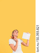 woman looking up holding menstruation calendar with copy space. Стоковое фото, агентство Ingram Publishing / Фотобанк Лори