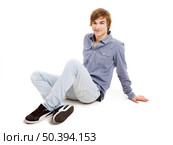 Happy young man sitting on the floor, over a white background. Стоковое фото, агентство Ingram Publishing / Фотобанк Лори