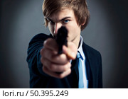Stressed businessman holding and pointing a gun to the camera. Стоковое фото, агентство Ingram Publishing / Фотобанк Лори