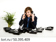 Businessman sitting with a bunch telephones on his front. Стоковое фото, агентство Ingram Publishing / Фотобанк Лори