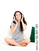 Beautiful woman on a sofa and listen music, isolated in white. Стоковое фото, агентство Ingram Publishing / Фотобанк Лори