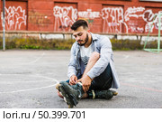 young man putting rollerskate outdoors court. Стоковое фото, агентство Ingram Publishing / Фотобанк Лори