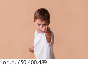 portrait boy clinching his fist fighting beige backdrop. Стоковое фото, агентство Ingram Publishing / Фотобанк Лори