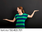 Happy woman making a scale with hands in front of a chalkboard . Стоковое фото, агентство Ingram Publishing / Фотобанк Лори