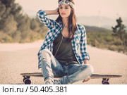 Beautiful young woman sitting over a skateboard. Стоковое фото, агентство Ingram Publishing / Фотобанк Лори