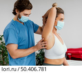 male osteopathic therapist with medical mask checking female patient s shoulder joint. Стоковое фото, агентство Ingram Publishing / Фотобанк Лори