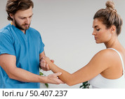 side view male osteopathic therapist checking female patient s elbow movement. Стоковое фото, агентство Ingram Publishing / Фотобанк Лори