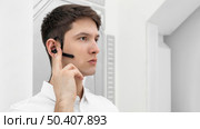 young man with hand prototype activating bluetooth headphone. Стоковое фото, агентство Ingram Publishing / Фотобанк Лори