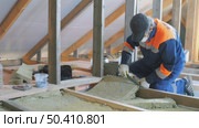 Insulation of a frame house with mineral wool. Cutting, fitting, laying insulation. Construction works. Стоковое видео, видеограф Константин Мерцалов / Фотобанк Лори