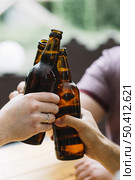 close up friends clinking with brown bottles. Стоковое фото, агентство Ingram Publishing / Фотобанк Лори