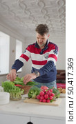 Russia, St.Petersburg, 22 June 2025: a man puts food on the table, plate of vegetables, green onion, red radish, lettuce, pomegranate, tomatoes and avocado, cereals, nutrition. Редакционное видео, видеограф Vladimir Drozdin / Фотобанк Лори