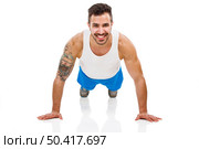 Athletic young man smiling and making pushups, isolated over a white background. Стоковое фото, агентство Ingram Publishing / Фотобанк Лори