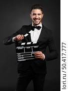 Portrait of a beautiful latin man with tuxedo and holding a clapboard. Стоковое фото, агентство Ingram Publishing / Фотобанк Лори