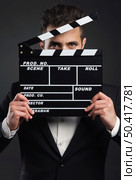 Studio portrait of a young man with a suit and holding a clapboard. Стоковое фото, агентство Ingram Publishing / Фотобанк Лори