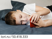 child laying bed using mobile phone side view. Стоковое фото, агентство Ingram Publishing / Фотобанк Лори