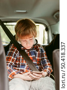 child playing smartphone car while road trip. Стоковое фото, агентство Ingram Publishing / Фотобанк Лори