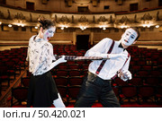 angry female mime artist hitting male mime with umbrella auditorium. Стоковое фото, агентство Ingram Publishing / Фотобанк Лори