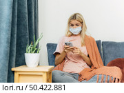 woman with medical mask smartphone home during pandemic. Стоковое фото, агентство Ingram Publishing / Фотобанк Лори