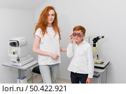 young female optician looking camera while examine boy patient eyes. Стоковое фото, агентство Ingram Publishing / Фотобанк Лори