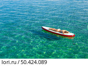 A beautiful woman sitting over a paddle surfboard and relaxing on a beautiful sunny day. Стоковое фото, агентство Ingram Publishing / Фотобанк Лори