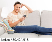 Beautiful woman sitting on a sofa with her phone and texting. Стоковое фото, агентство Ingram Publishing / Фотобанк Лори