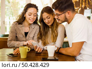 Friends studying together and watching something on the phone. Стоковое фото, агентство Ingram Publishing / Фотобанк Лори