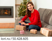 Beautiful woman at home wrapping presents for Christmas. Стоковое фото, агентство Ingram Publishing / Фотобанк Лори