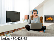 Beautiful woman working at home with a laptop while listen music. Стоковое фото, агентство Ingram Publishing / Фотобанк Лори