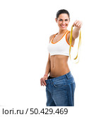 Woman with large jeans in dieting concept holding a measuring tape. Стоковое фото, агентство Ingram Publishing / Фотобанк Лори