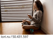 Woman sitting on the floor drinking a coffee and texting. Стоковое фото, агентство Ingram Publishing / Фотобанк Лори