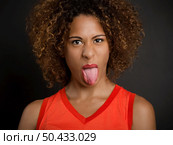 Portrait of a beautiful African American woman pulling her tongue out. Стоковое фото, агентство Ingram Publishing / Фотобанк Лори