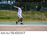 Tennis player hitting backhand at ball with racket on court. Стоковое фото, агентство Ingram Publishing / Фотобанк Лори