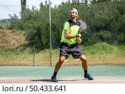 Tennis player hitting backhand at ball with racket on court. Стоковое фото, агентство Ingram Publishing / Фотобанк Лори