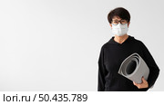 woman with medical mask holding fitness mat. Стоковое фото, агентство Ingram Publishing / Фотобанк Лори